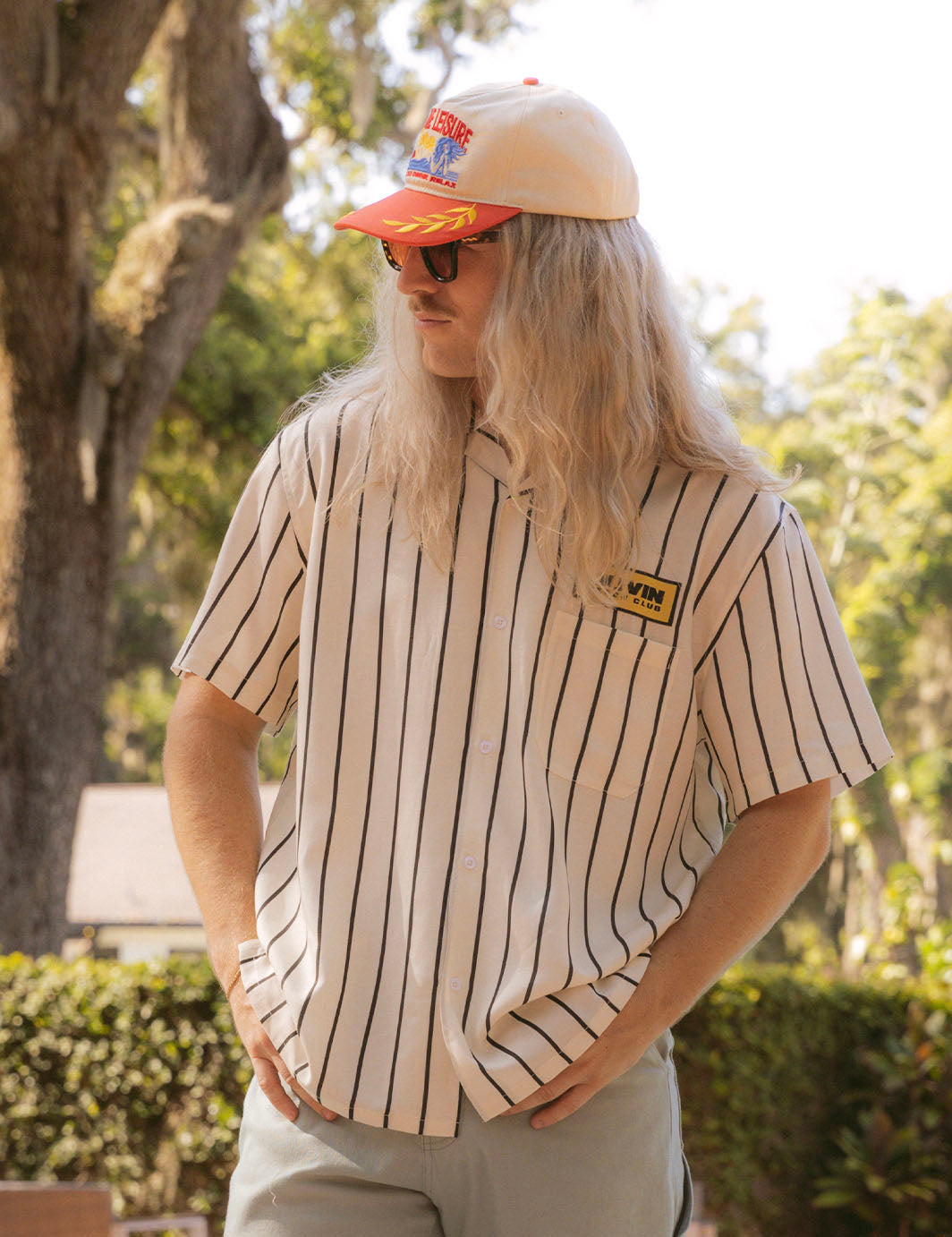 Man wearing a striped shirt and cap with a blurred outdoor background