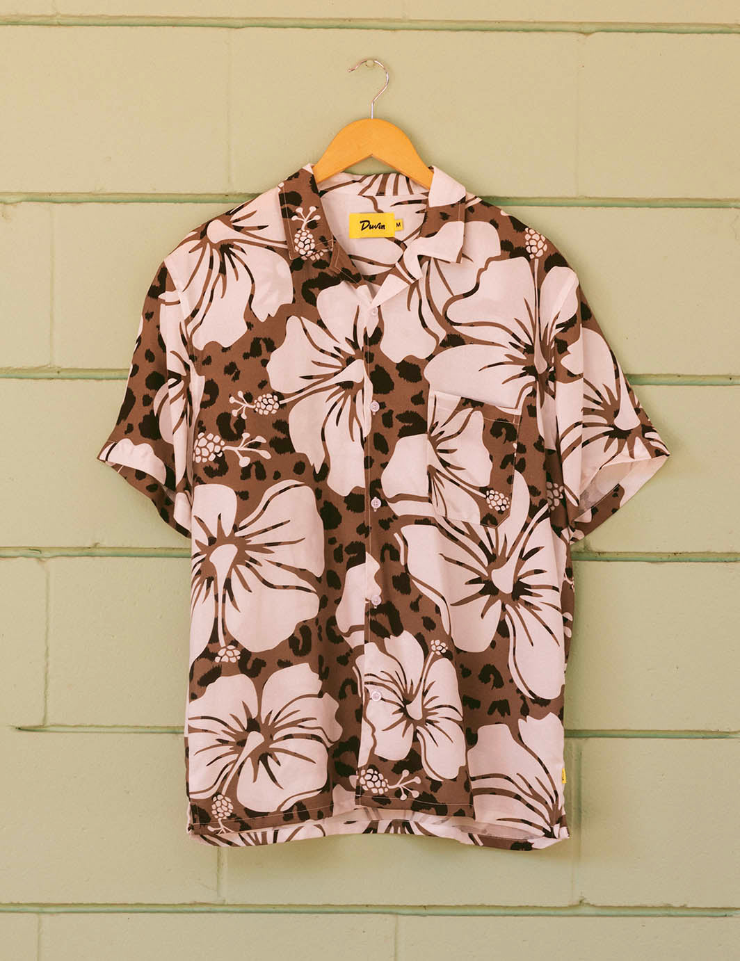 Floral patterned shirt on a hanger against a green wooden background